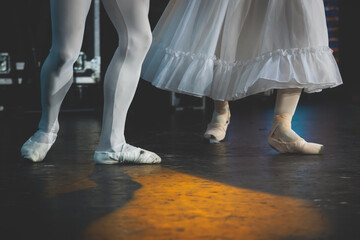 Ballet dancers couple during performance repetition, classic ballet rehearsal practicing in ballroom, view of legs in pointe shoes, ballerina and ballet dancer on a concert hall theatre stage © tsuguliev