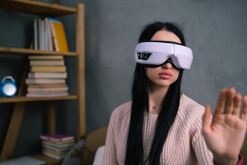 A girl is sitting in a room using virtual reality glasses. New technologies of the future in work...