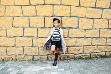Fototapeta na wymiar a little girl in a striped sweatshirt poses against a brick wall. children's autumn fashion. generation z