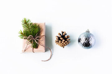 Christmas composition of a gift with Christmas tree branches, cones and a Christmas ball on a gray background, the concept of New year and Christmas, top view