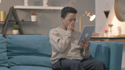 African Woman having Loss on Tablet on Sofa
