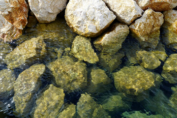 Big stones in shallow transparent turquoise sea water