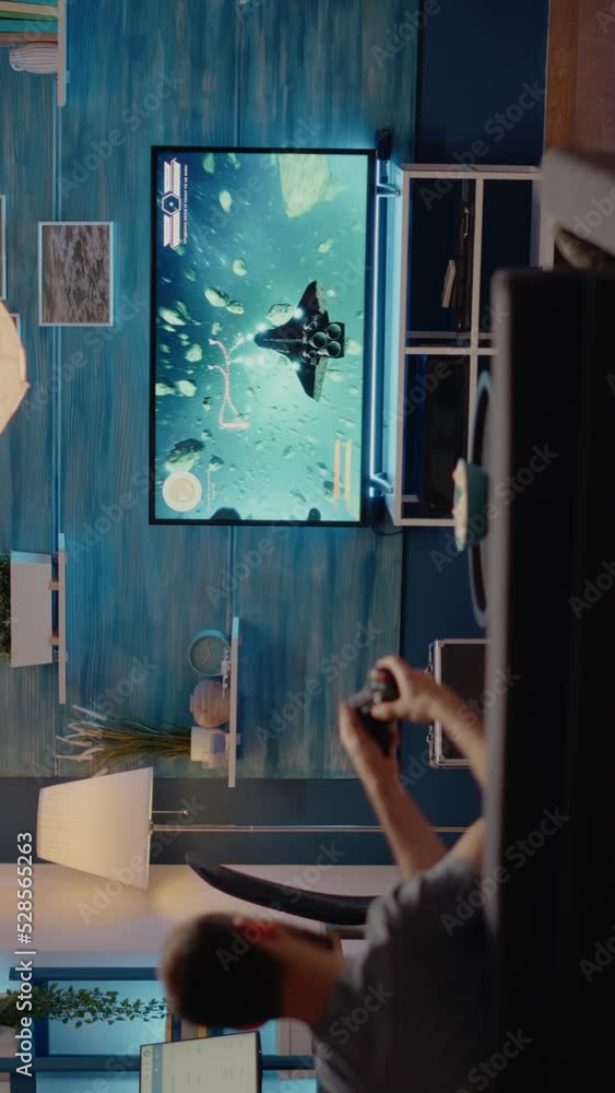Poster caucasian man playing video games on tv console using joystick while sitting on couch in living room