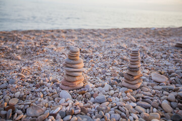 Fototapeta na wymiar Balanced harmony stones pyramid at beach coast. Summer sunset light. Zen meditation concept. 