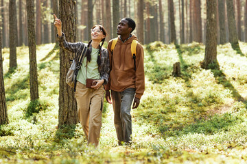 Multiethnic couple looking at beautiful nature while walking together in the forest