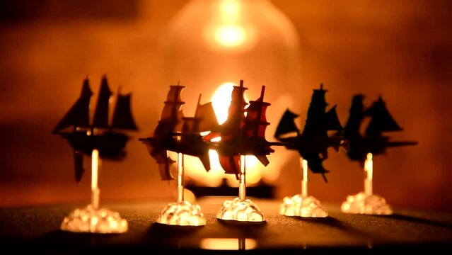 Board game Miniature Ship silhouettes rotating at lamp light tabletop footage