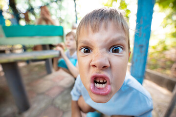 Angry young boy making grimace and expressing aggression - obrazy, fototapety, plakaty