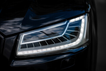 Headlight of Modern Prestigious Black Car Close Up.