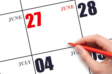 A hand holding a red pen and pointing on the calendar date June 27. Red calendar date, copy space,...