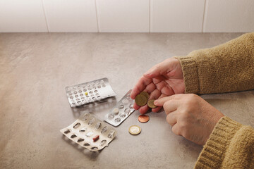 An elderly woman counts euro cents coins, she has run out of medicines
