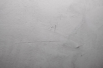 Texture of an old plastered white wall with deep scratches and cracks