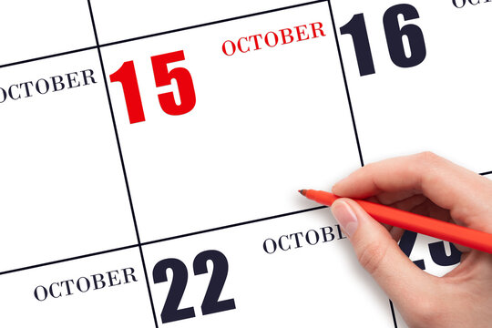 A hand holding a red pen and pointing on the calendar date October 15. Red calendar date, copy space, mockup.