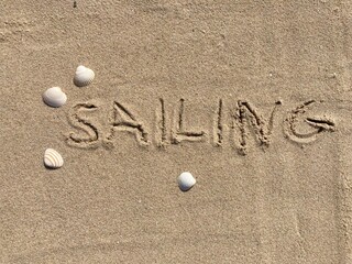 on the beach is carved with letters in the smooth sand the writing Sailing