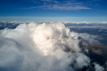 Aerial view from airplane window at high altitude of earth covered with puffy cumulus clouds...