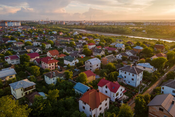 Obraz premium Aerial view of residential houses in suburban rural area at sunset