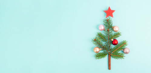 Christmas tree made from fir branches, red and pink baubles and a cinnamon stick as the trunk, greeting card with copy space