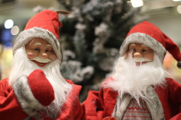 two smiling santa claus with christmas tree