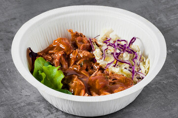 BOWL with pulled pork , gravy and Cole Slaw salad. in a plastic takeout container