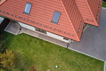 Closeup of attic windows on house roof top covered with ceramic shingles. Tiled covering of building