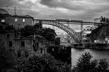 Abandoned buildings on the banks of the Douro with Dom Luis I Bridge in the background, Porto, Portugal. Black and  white photo.