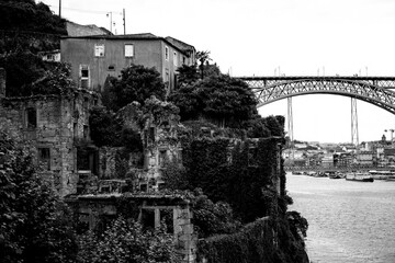 Abandoned ruins of a building on the banks of the Douro with Dom Luis I Bridge in the background in Porto, Portugal. Black and  white photo.