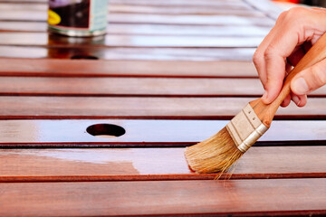 Apply teak oil on the boards of a wooden table to protect it from bad weather.