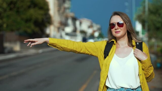 Woman with backpack catching car on the road. Travel by autostop.