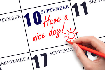 The hand writing the text Have a nice day and drawing the sun on the calendar date September  10