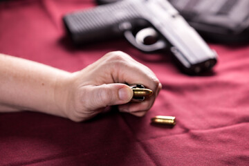 Hand holding a pistol magazine pushing bullets free with the thumb