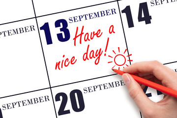 The hand writing the text Have a nice day and drawing the sun on the calendar date September  13