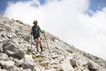 Naklejka premium Woman Tourist Hiker Descending from the Summit of a High Mountain