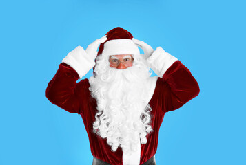 Portrait of emotional Santa Claus on light blue background