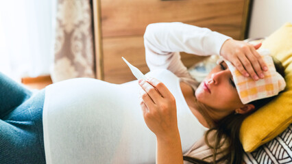 Pregnancy flu thermometer. Pregnant woman holding thermometer, check fever flu temperature. Pregnancy girl sick. Therapy, healthcare, motherhood concept.