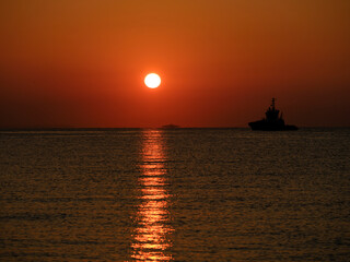 Fototapeta na wymiar a ship leaving port at sunrise