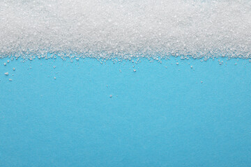 Fototapeta na wymiar Granulated sugar on light blue background, top view. Space for text