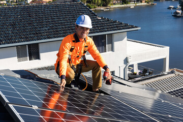 Solar panel technician with drill installing solar panels