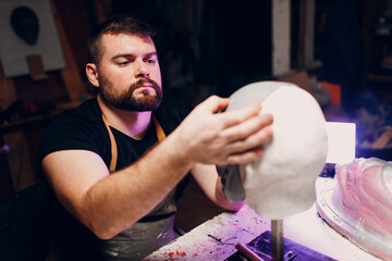 Artisan craftsman create mask based on plaster cast. Gypsum mold and plastic mask sculpting.