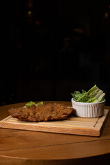Milanese with topping. Milanesa covered with arugula, tomatoes, cheese. Breaded meat. Italian food. Fried meat. Beef, chicken meat, pork meat.