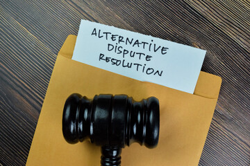Alternative Dispute Resolution text on document with gavel above brown envelope.