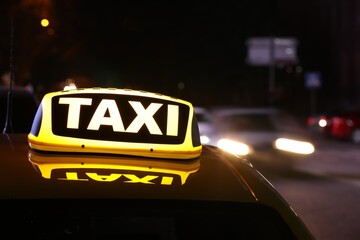 Taxi car with yellow sign on city street at night, closeup