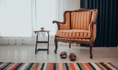 vintage style armchair wooden, turkish coffee and lace doily under coffee, colourfull handmade rug and women's slippers, curtain behind them near window - obrazy, fototapety, plakaty