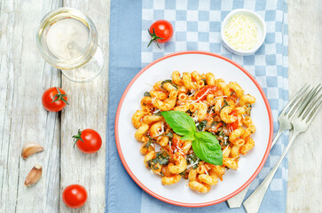 Tomato basil pasta in a plate on a wood background