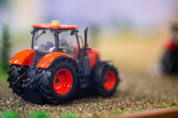 Orange toy tractor laying on the ground in the garden where the background was blurred.