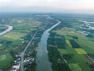 Top view of the Sakae Krang River, Uthai Thani Province where both sides of river are filled with lush green trees. There are community near waterside.