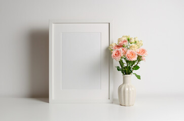 Vertical frame mockup in white interior with copy space for artwork and fresh roses