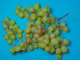 Grapes on the table. Kishmish on a blue surface. Grapes of different colors. A bunch of berries on a bright background. Wine ingredient.