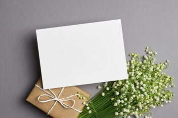 Greeting or invitation card mockup with gift and lily of the valley flowers