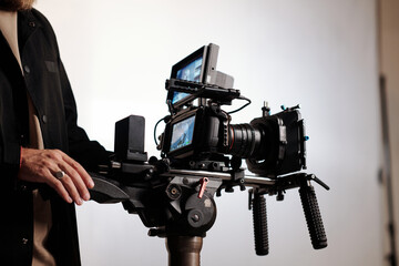 Close-up of cameraman or director of shooting team using steadicam while standing in studio and...
