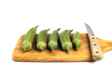 green okra pods on cutting board with a knife. Isolated on white.