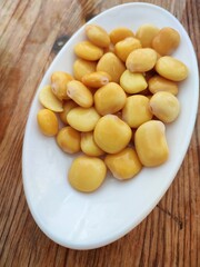 Tasty lupins in a white plate on a wooden table.